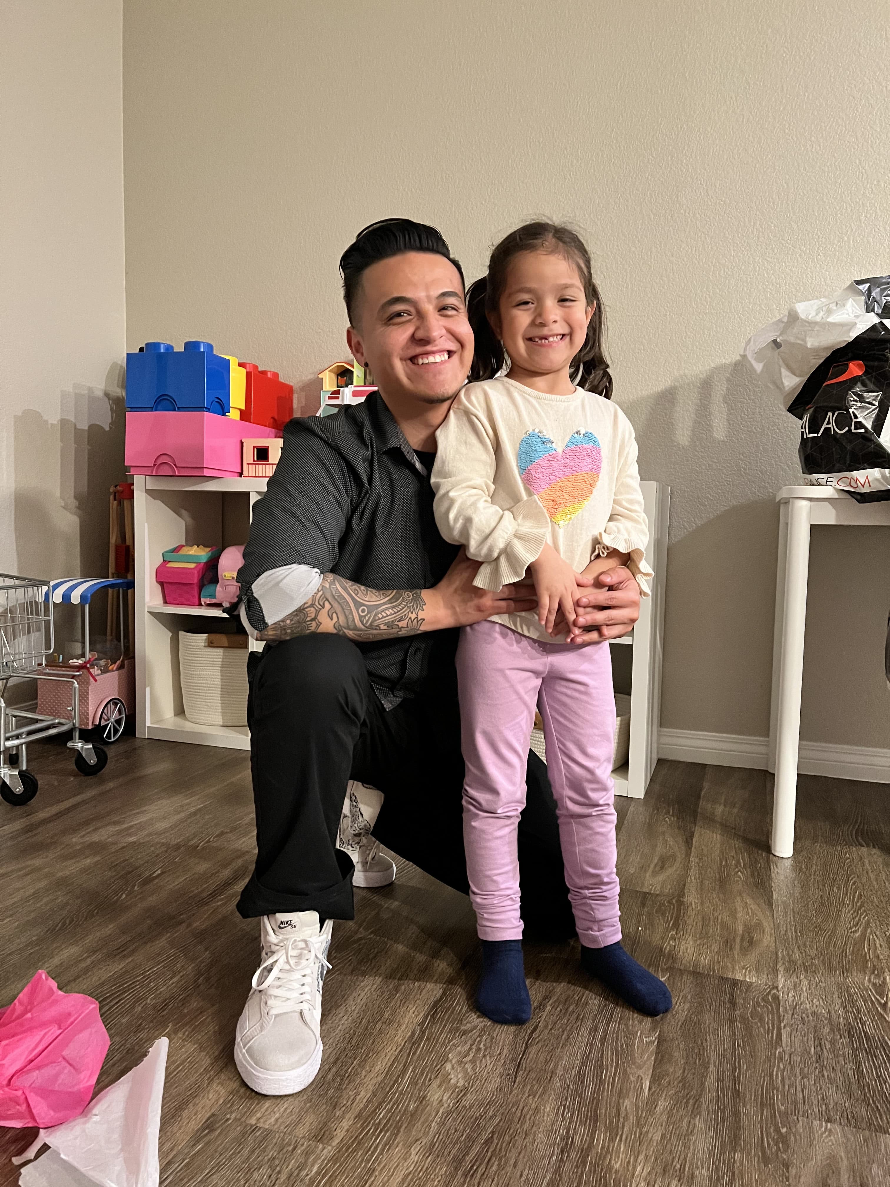 The founder kneeling beside his smiling daughter in their playroom
